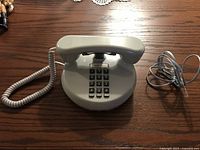 Full view of telephone with handset on base, coiled cord and line cord visible