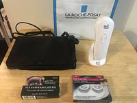 All items: black leather bag, RoC massager on cradle, Ardell adhesive box, Revlon lashes