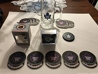 Lot overview showing mug, ornament box, boxed puck coasters, stacks of paper coasters and single black coaster