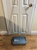 Full view of sweeper with handle upright against door