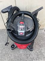 Full view of shop vacuum with hose and nozzle attached