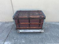 Front view of steamer trunk showing wood slats, metal strapping and clasp hardware