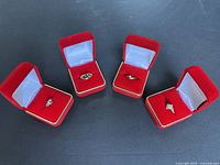 Group shot of four rings in red velvet boxes