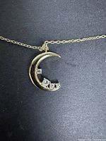 Close-up of moon pendant with stones on chain