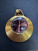 Front view of gold-plated pendant watch showing full case and dial