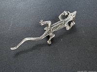 Top view of sterling silver lizard brooch with marcasite and red eyes