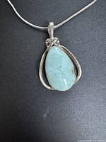Close view of pendant showing blue cabochon stone and silver setting
