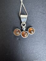 Close-up of pendant showing three amber cabochons and bail