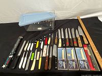 Overview of entire lot including loose knives, sealed EKCO knives, boxed knife, measuring stick for scale