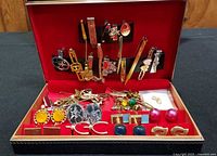 Full view of open case with assortment of tie clips, cufflinks and pins