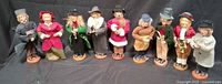 Group shot of nine vintage caroler figurines on black backdrop