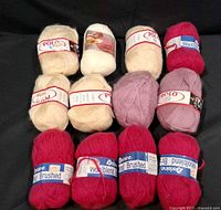 Group of 12 skeins showing cream, lavender and red shades with labels visible