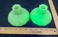Pair of uranium glass candle holders glowing under UV beside ruler