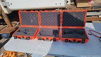 Three orange Nanuk cases open showing foam interiors
