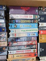 Open box showing multiple VHS titles including The Deer Hunter, Mrs. Doubtfire, Wizard of Oz etc.