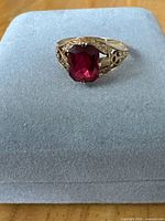 Front view of gold ring with red stone on display pad