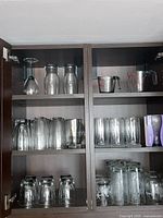 Cabinet shelves showing variety of glasses and measuring cups
