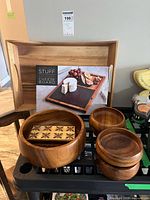 Lot overview showing boxed cheese board, wooden tray, salad bowls