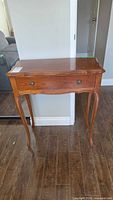 Front view of wood side table with drawer and cabriole legs