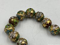 Close-up of several cloisonné beads showing enamel colours and floral motifs