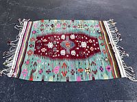 Full view of flatwoven kilim rug on dark surface