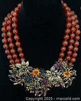 Necklace on bust showing three strands and floral bib