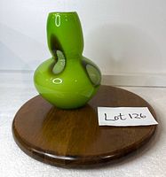 Front view of green cased glass vase on round wooden stand
