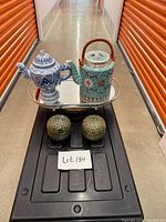 Overall lot showing two teapots on mirror tray and two spherical lidded cups below