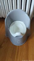 Front view of gray Baby Björn potty chair with white insert