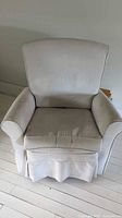 Front view of ivory upholstered swivel armchair showing seat cushion and skirt