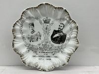 Front view of commemorative porcelain plate showing portraits, text, scalloped gilt edge