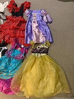 Overview of Rapunzel gown, yellow gown, red polka-dot dress, teal Ariel dress and purple shoes
