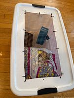 Overhead view of enclosure showing mesh lid, wheel, wood hide, bedding bag