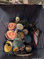 Overview of bin showing assorted cups, juicer, bottle, figurine, earbuds