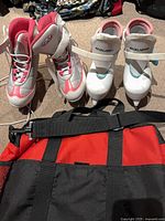 Two pairs of kids ice skates and red/black bag laid out