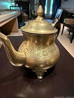 Front view of etched brass teapot on feet