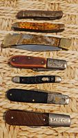All seven pocket knives laid out showing handles and blades