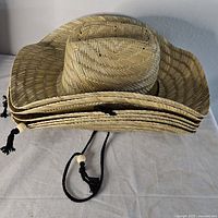 Stack of four straw cowboy hats showing crowns and brims