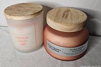 Both candles side by side showing jars and wooden lids