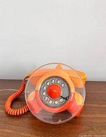 Front view of orange airplane rotary phone showing dial and cord