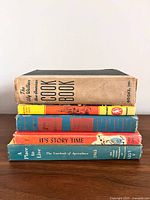 Stack of four books showing spines: The Cook Book, orange-spined children’s book, It's Story Time, A Place to Live