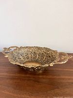 Side view of solid brass openwork bowl with handles