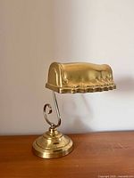 Full view of brass banker lamp on wood surface
