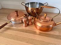 Group shot of kettle, sauté pan with lid, colander, salt mill and pepper mill