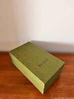 Closed Gucci green embossed shoe box on wooden surface