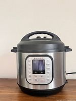 Front view of stainless steel Instant Pot showing lid, handles, and control panel