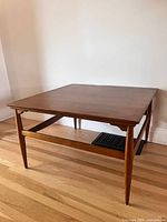 Full view of square wood coffee table showing top, legs, stretchers