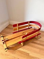 Full view of wooden sled with red side rails