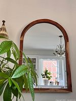 Front view of wooden arched mirror hung on wall