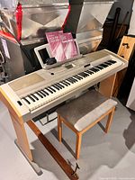 Full view of Yamaha DGX-500 on stand with bench and song books